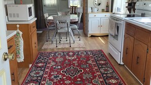 Una cocina compacta con armarios de madera, un microondas, una estufa y una zona de comedor con una mesa y sillas.