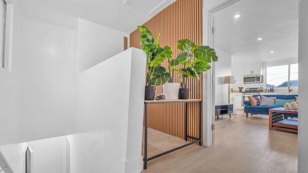 Een moderne leefruimte met een trap, een houten scheidingswand en een keukenhoek.
