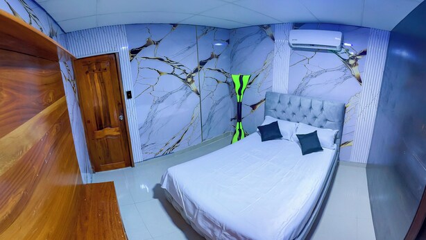 Un dormitorio con una cama, una puerta de madera y una pared con diseño de mármol.