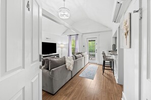 Una sala de estar moderna con un sofá gris, un televisor de pantalla plana y una zona de comedor con mesa y sillas.