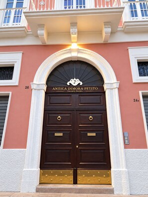 Een dubbele deur ingang met een bord erboven waarop staat 'ANTICA DIMORA PETITO Luxury Suites'.