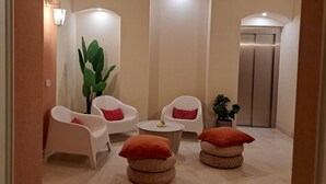 Un pasillo con sillas blancas, una mesa redonda y una planta en maceta.
