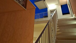 Una escalera con barandilla metálica que lleva a un balcón con pared azul y barandilla decorativa.