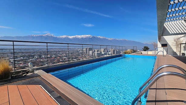 A rooftop pool with a view of snow-capped mountains and a cityscape.