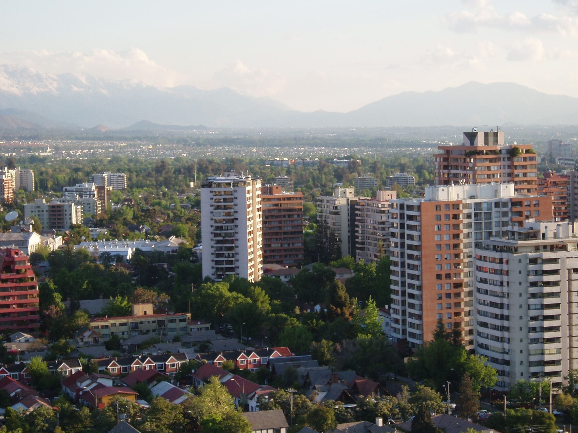 A cityscape with high-rise buildings, residential houses, and mountains in the background.