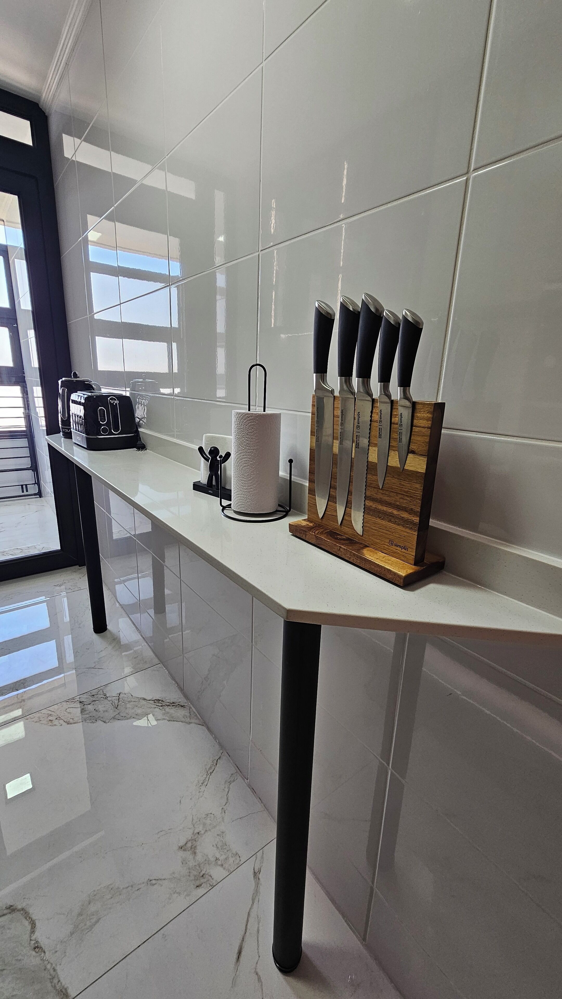 A kitchen counter with a knife block, a paper towel holder, and a toaster.