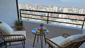 A balcony with two wicker chairs and a small round table with breakfast items.