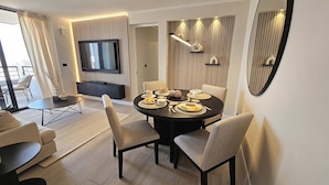 A modern dining area with a round table, six chairs, and a TV mounted on the wall.