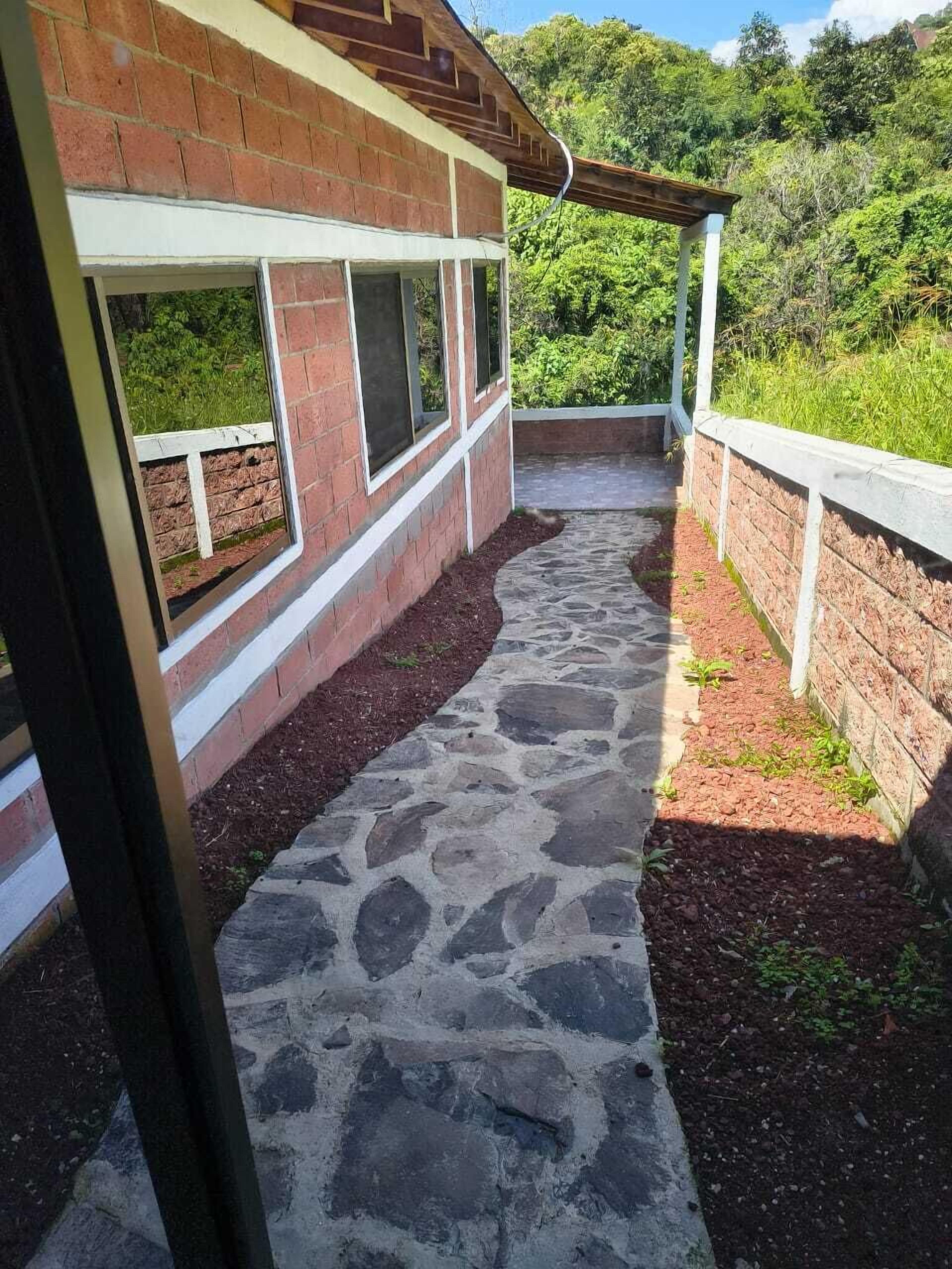 A covered outdoor area with a stone floor, brick walls, and a white railing.