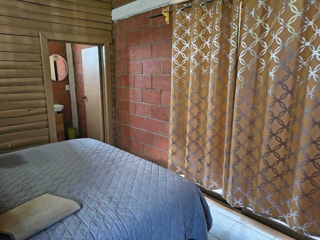 Een slaapkamer met een bed, een bakstenen muur en een gordijn.
