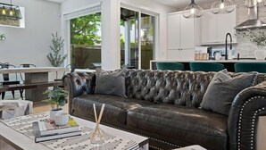 A modern living room with a leather sofa, dining area, and kitchen. - Spacious 5BR Central Austin Home w/Pool, Sleeps 13 (Austin)