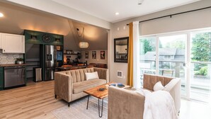 Una cocina moderna con refrigerador integrado, un comedor con mesa de madera y una sala de estar con sofá y mesita de centro.