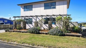Une maison moderne à deux étages, dotée d’un patio couvert et d’un jardin aménagé.