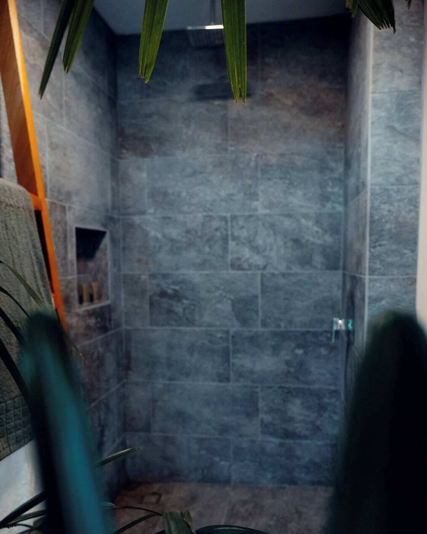 Un baño con pared de piedra, toallero y planta.