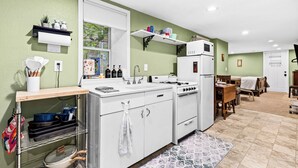 A compact kitchen with white appliances, a wooden countertop, and a dining area with a table and chairs. - Nostalgia Nook - Vintage Studio (Duluth)