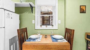 A dining table set with plates, glasses, and cutlery, flanked by wooden chairs, against a green wall with a window above. - Nostalgia Nook - Vintage Studio (Duluth)