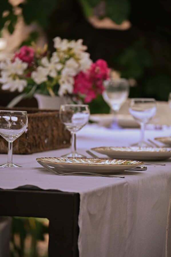A table set for a meal with wine glasses and plates, surrounded by flowers. - Le Mas de la Digue - Provence (Châteaurenard)