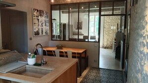 A modern kitchen with a wooden dining table, a sink with a faucet, and a patterned rug.