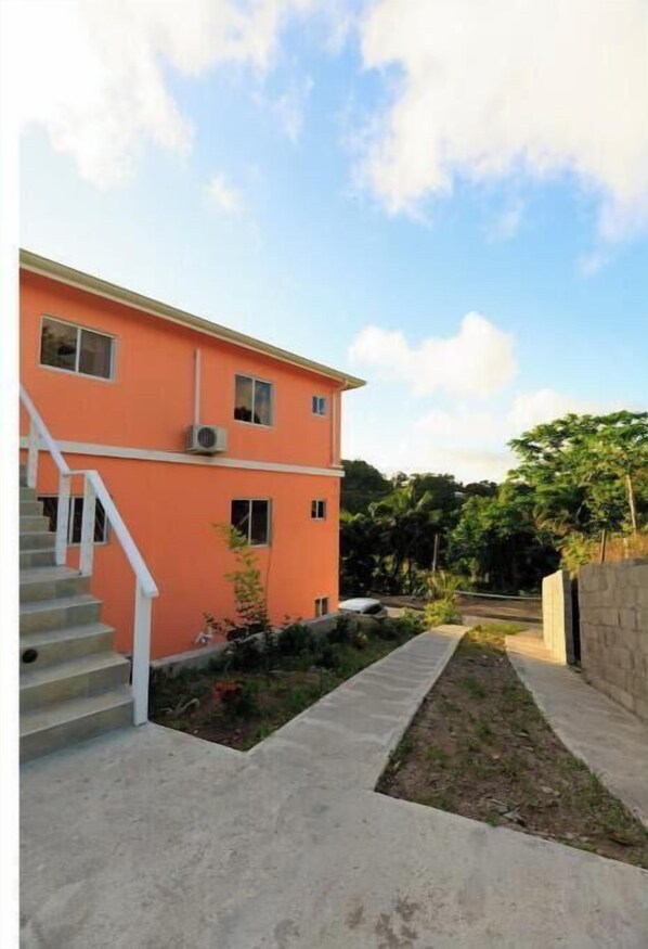 A two-story building with a concrete staircase leading to the entrance. - Chateau Michelle - 2BR Piton View Apartment in Villa - Top Floor (Soufrière)