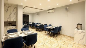 A dining area with marble walls, blue chairs, and a patterned floor. - Hotel The Best Delhi Airport (New Delhi)