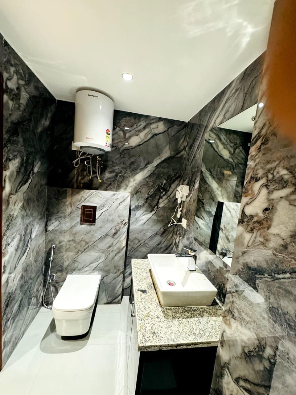 A bathroom with a white toilet, a sink, a mirror, and a shower.