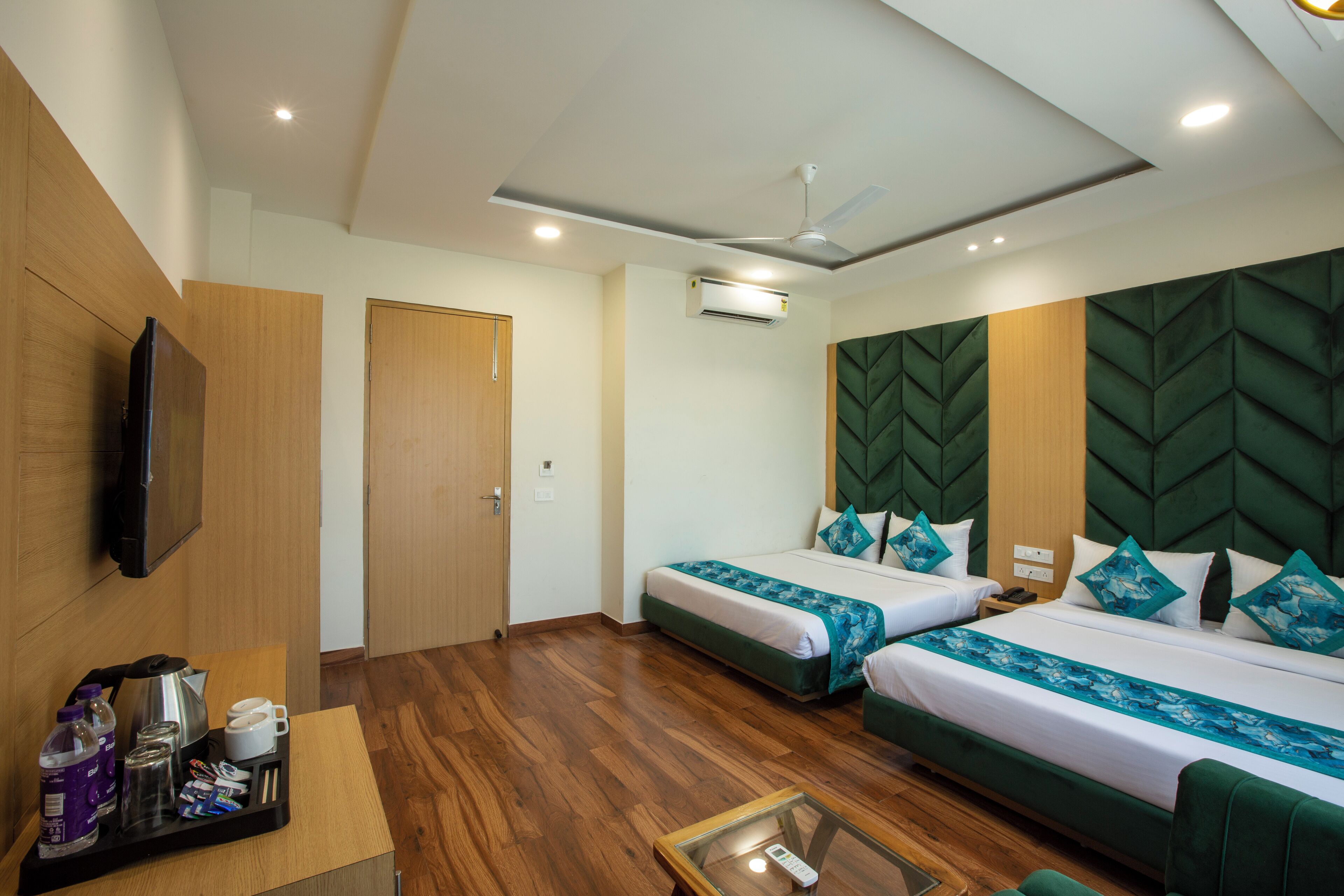 Une chambre d’hôtel avec deux lits, une télévision, un ventilateur de plafond et un coin café.