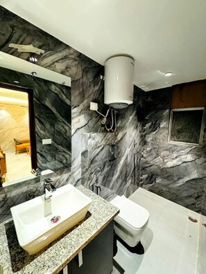 A modern bathroom with a marble wall, a sink, a toilet, and a shower. - Hotel The Best Delhi Airport (New Delhi)