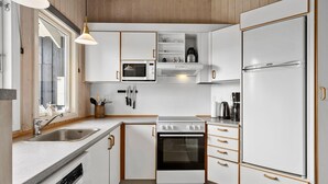 A compact kitchen with white cabinetry, a built-in oven, a microwave, and a refrigerator.