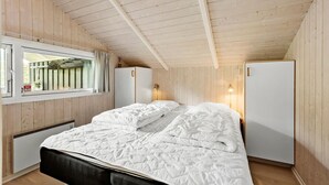 A bedroom with a bed, a window with curtains, a bedside lamp, and a white wardrobe.