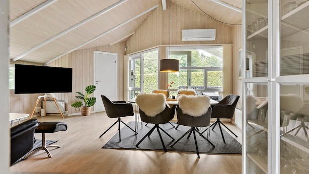 A modern, open-plan living space with a high ceiling, wooden walls, and large windows.