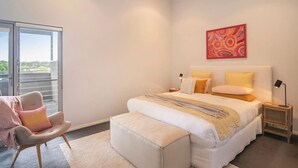 A bedroom with a bed, a chair, a bedside table, a lamp, and a painting on the wall. - Luka on Town View Terrace (Margaret River)