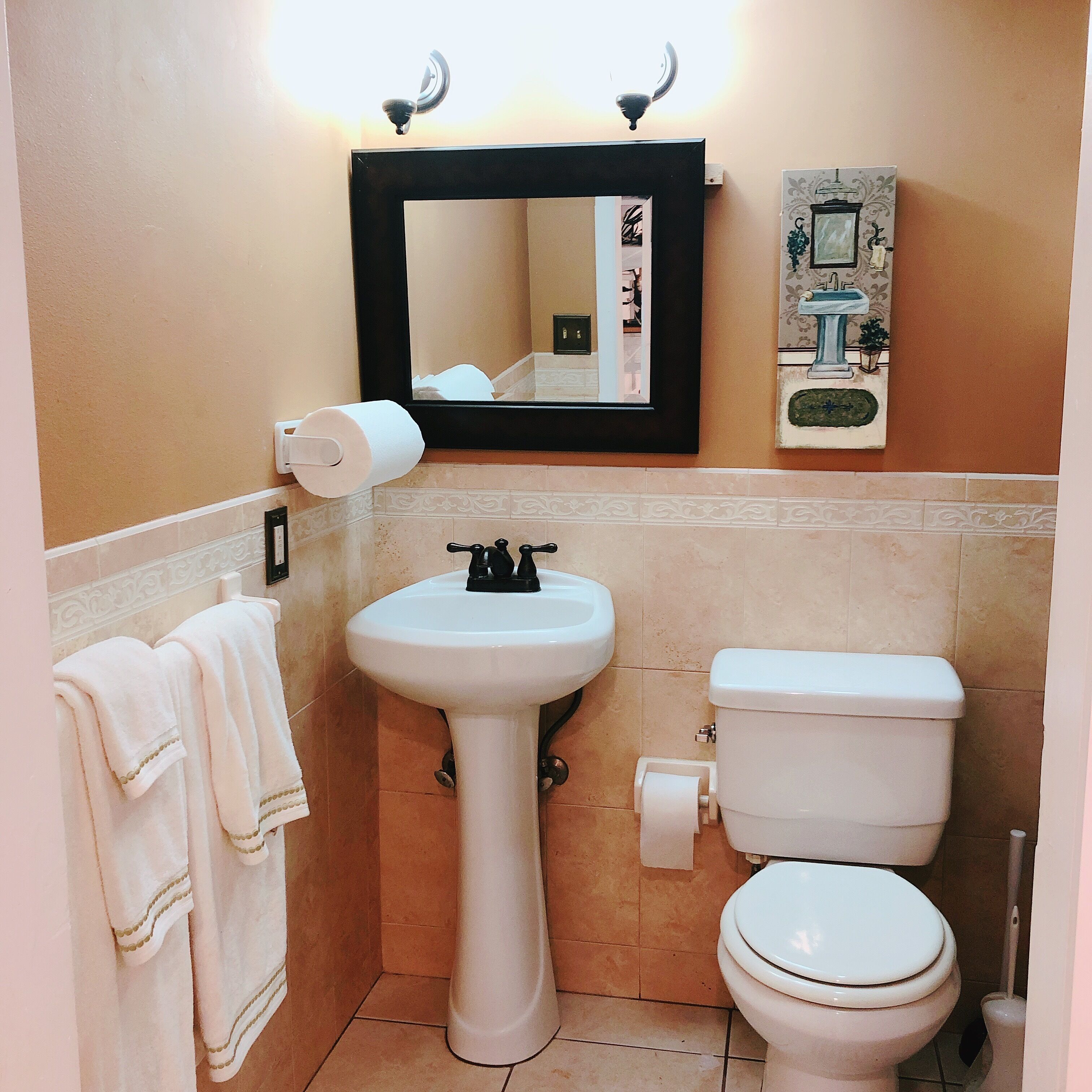 A bathroom with a pedestal sink, toilet, and a mirror above the sink.