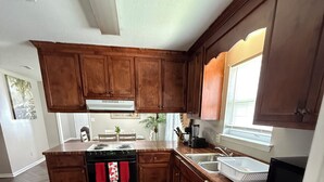 Une cuisine avec des meubles de rangement en bois, une cuisinière, un lave-vaisselle et une fenêtre.