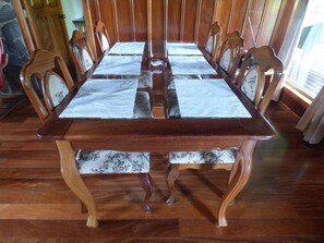 Une table de salle à manger en bois, accompagnée de quatre chaises, chacune dotée d’un coussin orné de motifs floraux.