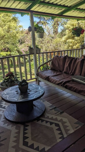 A covered patio with a round table, a cushioned seating area, and potted plants. - Unique, spacious, and comfortable Chalet in ideal Monteverde location. (Monteverde)