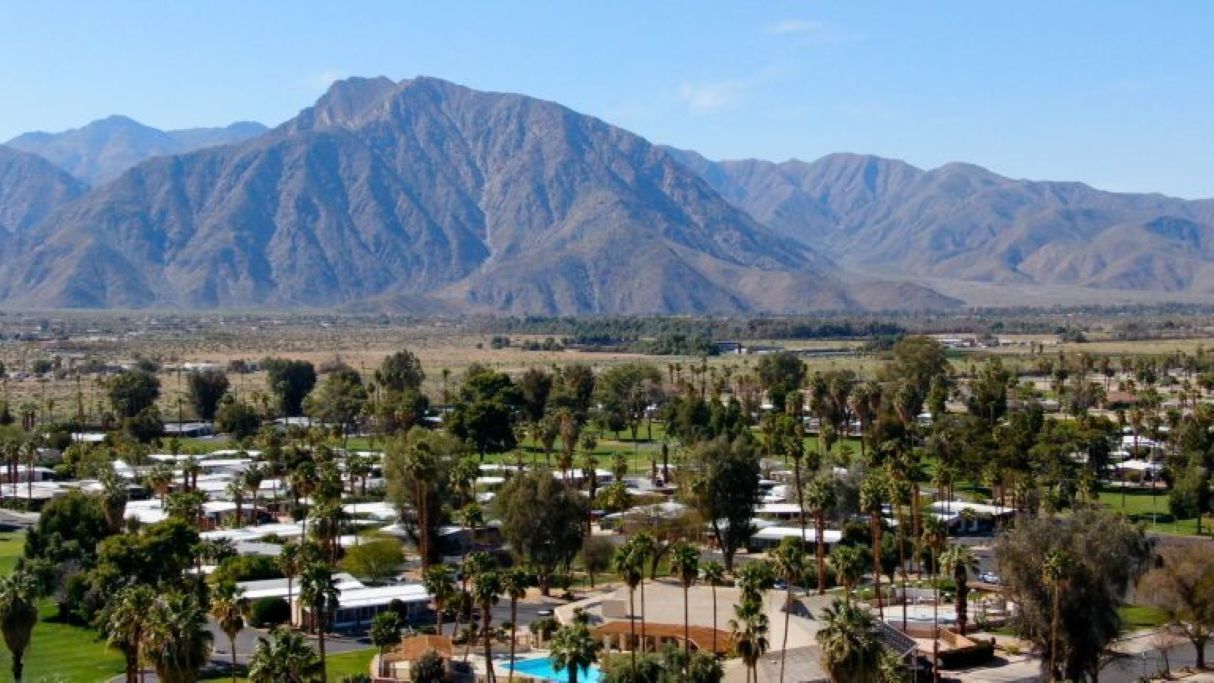 Un resort con varias villas, una piscina y montañas al fondo.