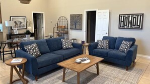 Ein Wohnzimmer mit zwei blauen Sofas, einem Holztisch und einem gemusterten Teppich.