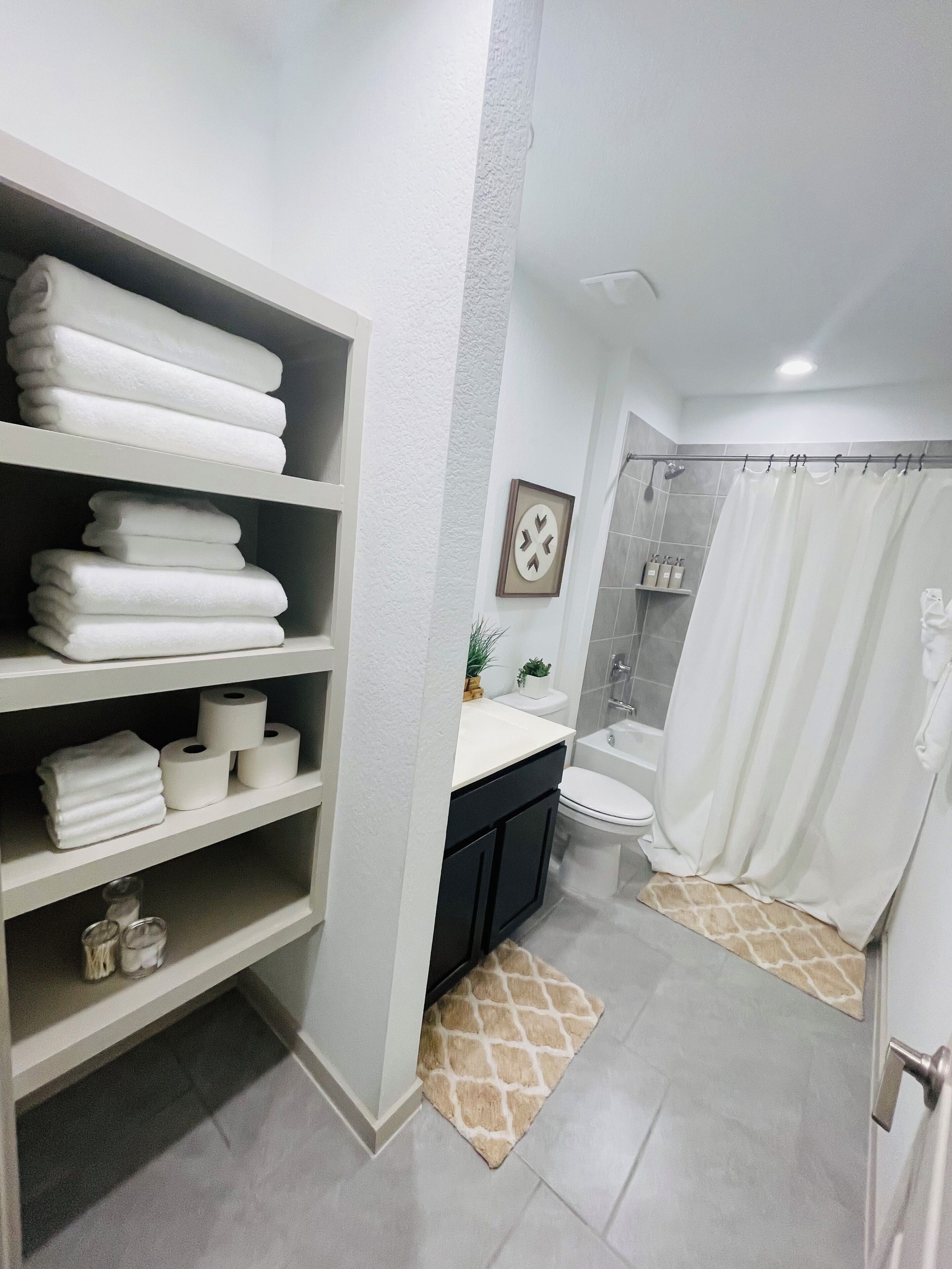 Ein Badezimmer mit Dusche, Toilette und Regalen mit Handtüchern.