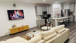 Ein modernes Wohnzimmer mit einer Couch, einem Couchtisch und einem Fernseher, der einen Kamin zeigt.