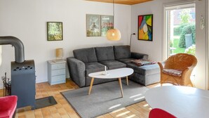 A modern living room with a grey sofa, a white coffee table, a wicker chair, and a small side table with a lamp. - Lovely home in Tranekær with WiFi (Tranekær)