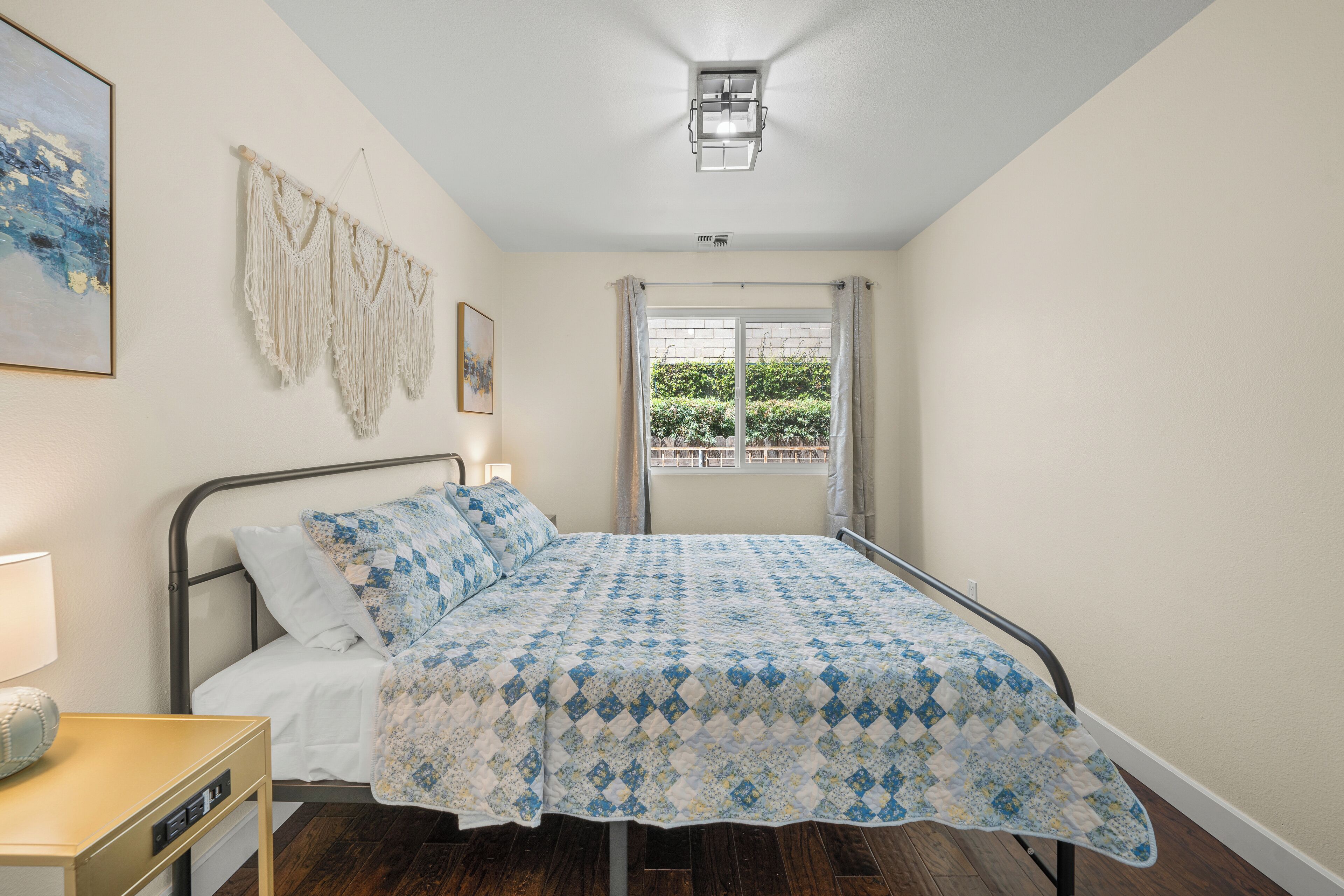 A bedroom with a bed, bedside table, and a window with curtains.