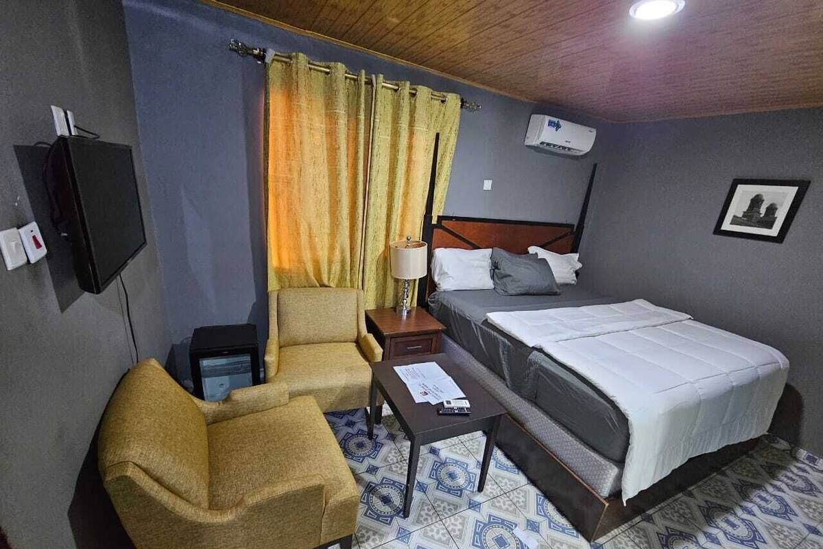 A hotel room with a bed, a chair, a desk, and a nightstand.