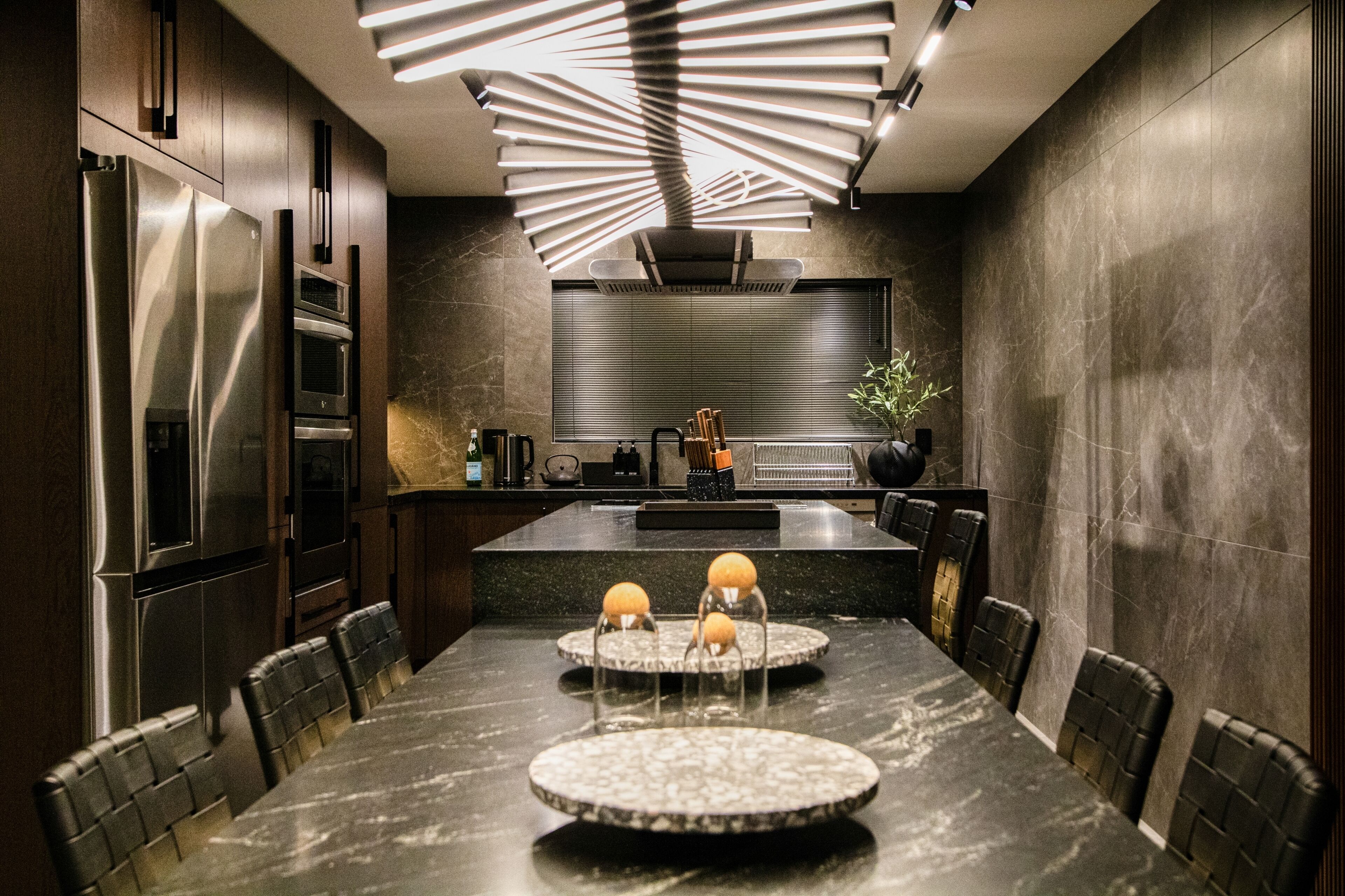 Una cucina moderna con un'isola grande, mobili scuri e un lampadario dal design originale.