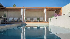 Ein moderner Poolbereich im Freien mit Liegestühlen und einer Pergola.