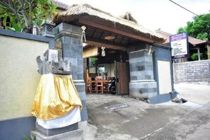 A building entrance with a thatched roof, a statue, and a signboard. - Menjangan Sari (Bali)