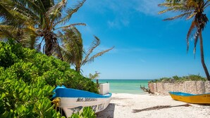 A beach with two boats, one blue and one yellow, and a clear blue sky. - Welcome to this 1 bed 1 bath condo with splendid pool view (Progreso)