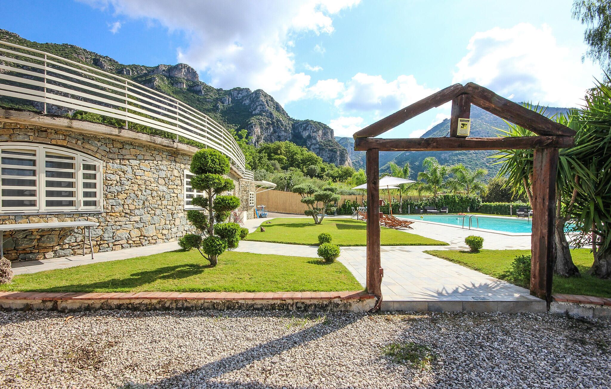 Un bâtiment en pierre doté d’un toit incurvé, d’une piscine et surplombant un paysage montagneux.
