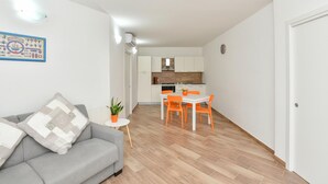 A compact living space with a grey sofa, a small round table with a plant, and a dining area with orange chairs. - Stunning home in Giungano (Giungano)