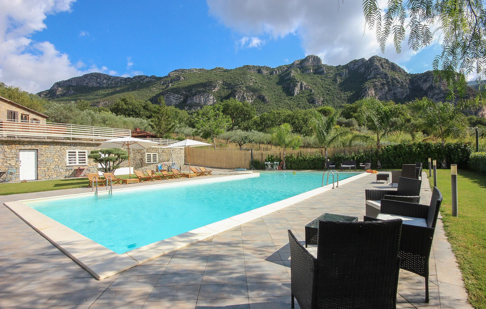 A swimming pool with lounge chairs and a stone building in the background.