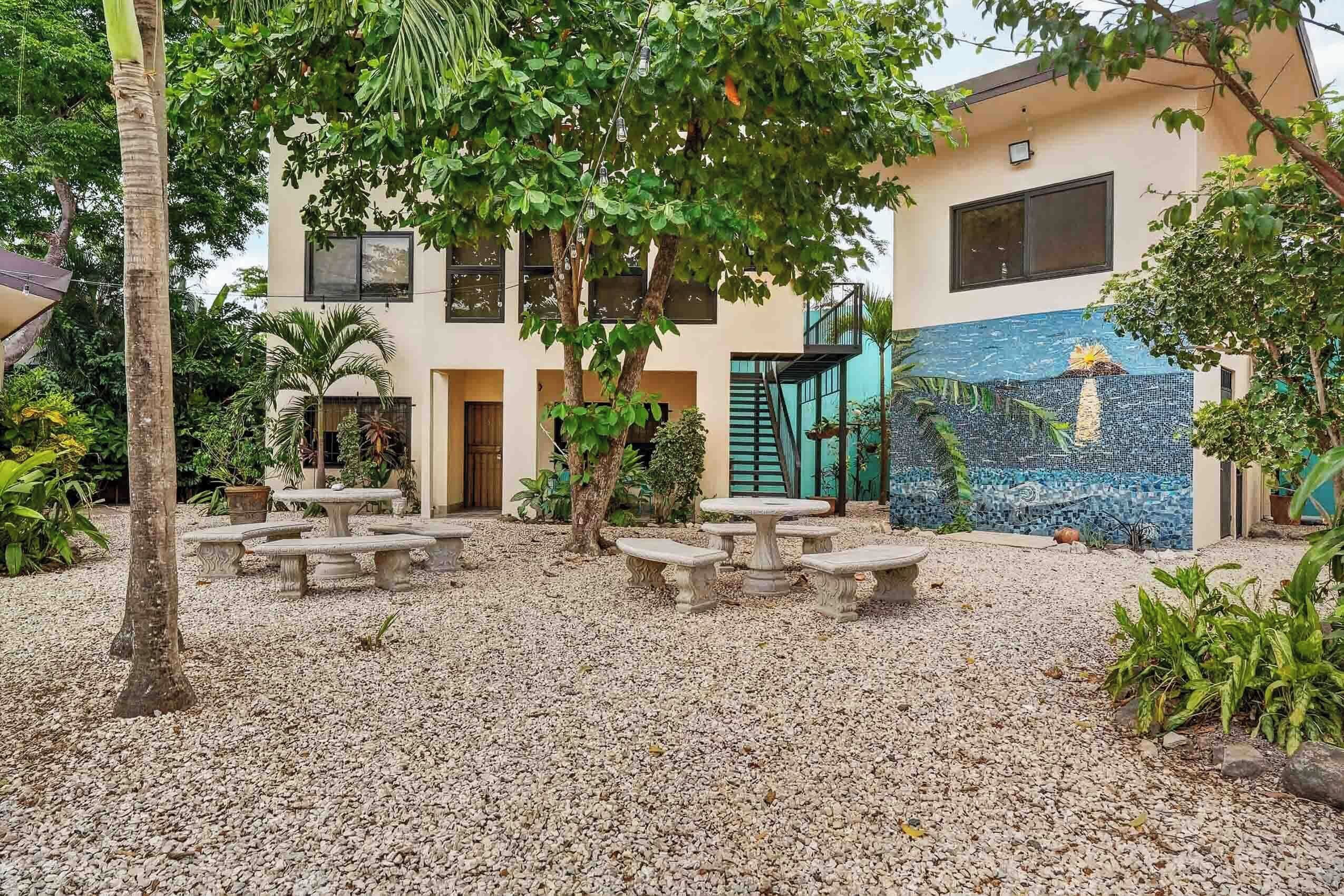 A courtyard with a seating area, palm trees, and a building with a blue mosaic wall.
